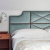 An upholstered headboard in light blue silk velvet with decorative nailings in a white, modern bedroom - Beaumont & Fletcher